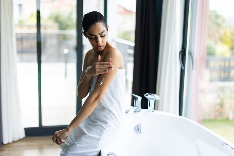 Woman taking care of her skin, applying body cream
